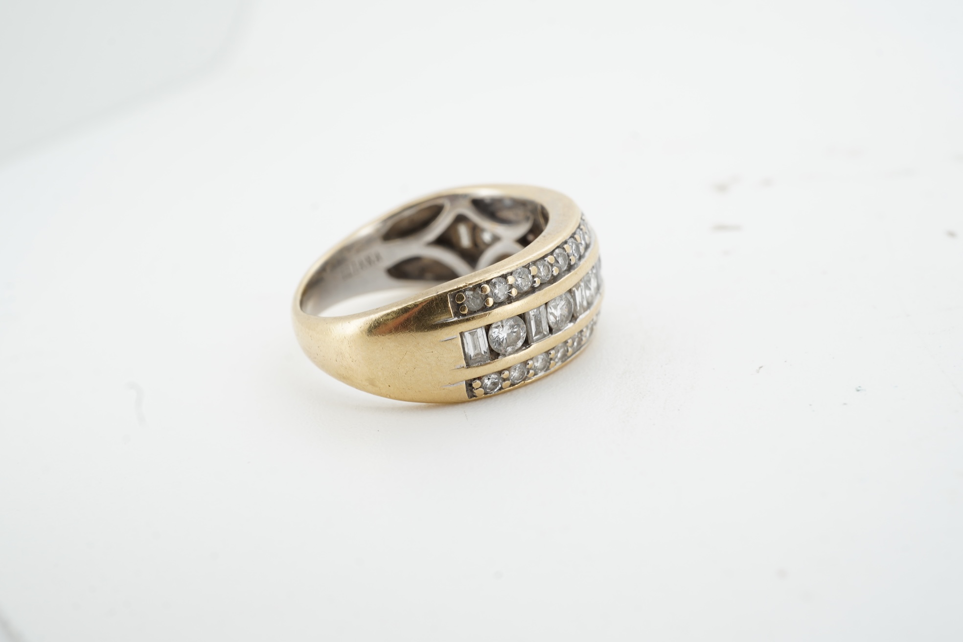 A diamond ring, the wide band set with a line of alternating brilliant-cut and baguette diamonds, between bands of brilliant-cut diamonds, mounted in gold, size M, British hallmarks for 18ct gold, total diamond weight ap